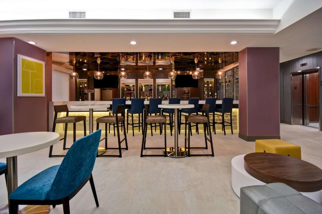 皇后区Hampton Inn NY-JFK的有桌椅和酒吧的餐厅