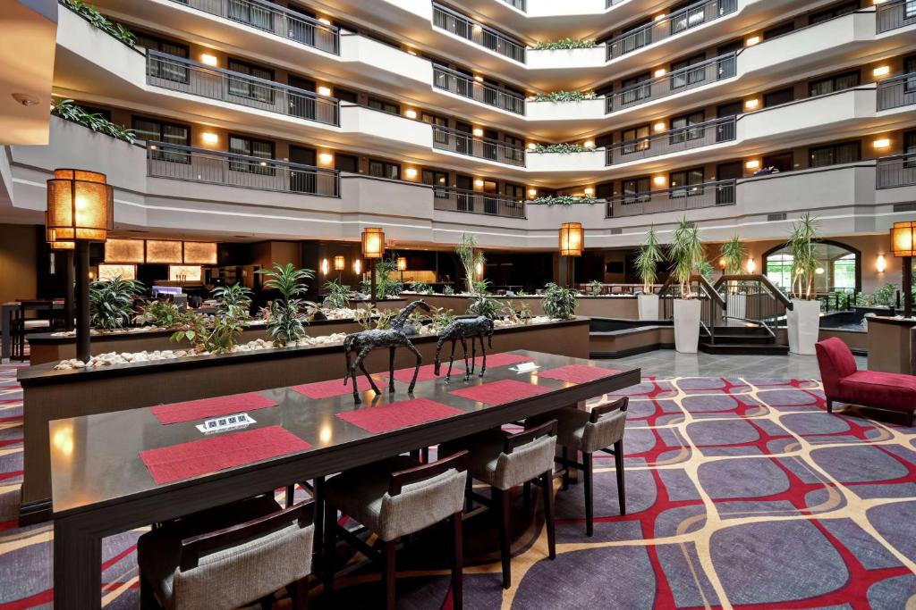赫恩登Embassy Suites by Hilton Dulles Airport的酒店大堂设有长桌子和椅子