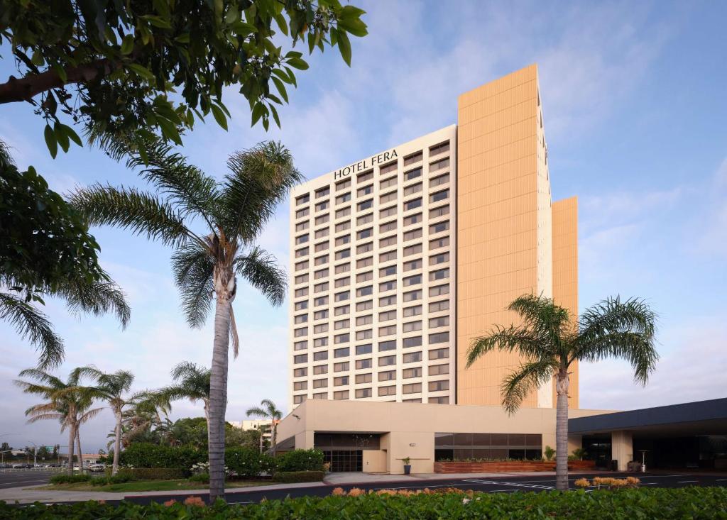 安纳海姆Hotel Fera Anaheim, a DoubleTree by Hilton Hotel的一座酒店大楼前面有棕榈树