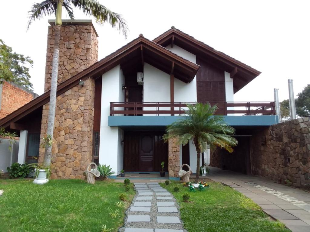 乌鲁瓜亚纳Pousada A Cabana的带阳台和棕榈树的房子