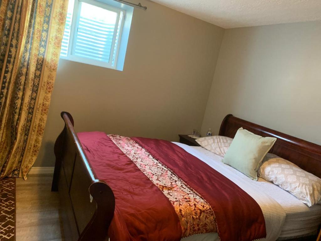 卡尔加里Steven Abode的一间卧室配有一张带红色毯子的床和窗户。