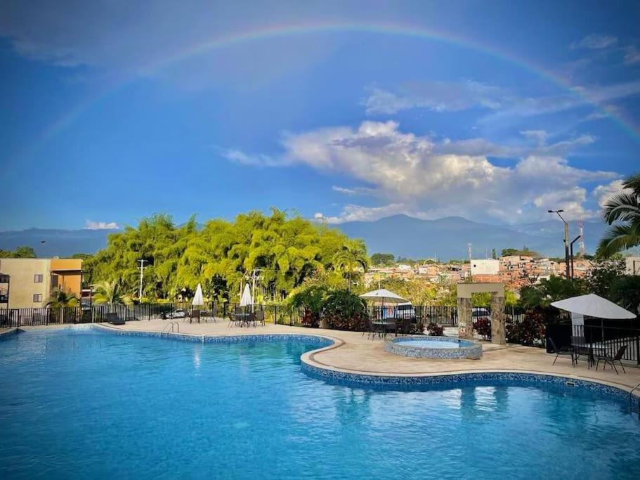 拉特瓦伊达Atardecer Quindiano的度假村内的大型游泳池,配有桌椅