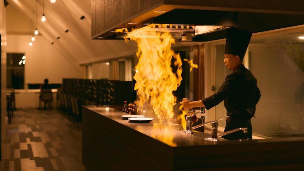 草津Fourtreat Kusatsu的厨师在厨房烹饪,厨房的壁炉在柜台上