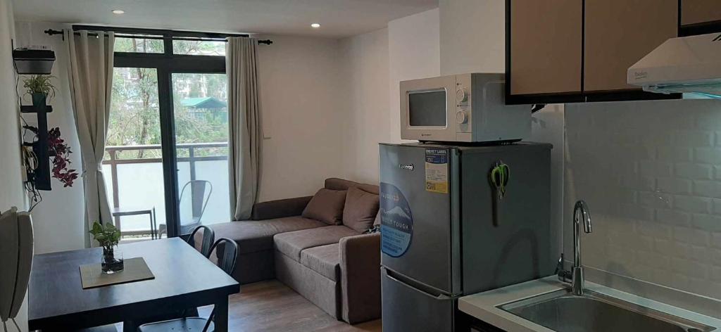 碧瑶Gabs CozyHomes at MegaTower IV Condo, City Center Baguio的厨房以及带冰箱和沙发的客厅。