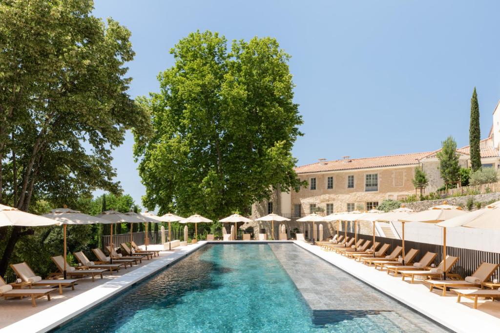 曼讷Le Couvent des Minimes Hôtel & Spa L'Occitane的一个带躺椅和遮阳伞的游泳池