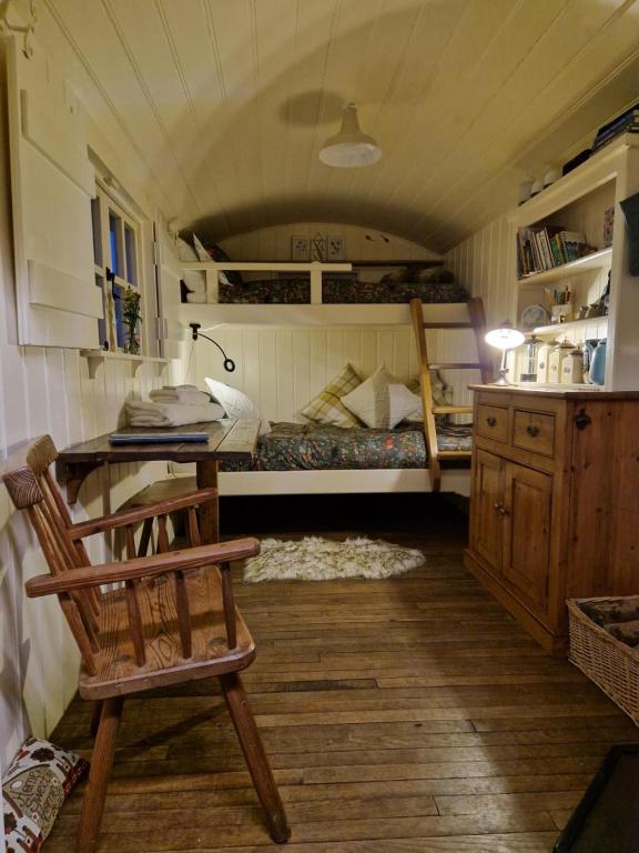科姆堡The Delkin Shepherds Huts Castle Combe的客房设有一张床、一张桌子和一把椅子。