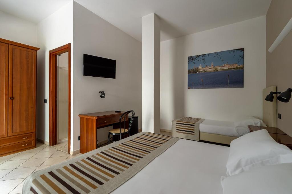 曼托瓦Hotel Mantegna Stazione的一间卧室配有一张床、一张书桌和一台电视