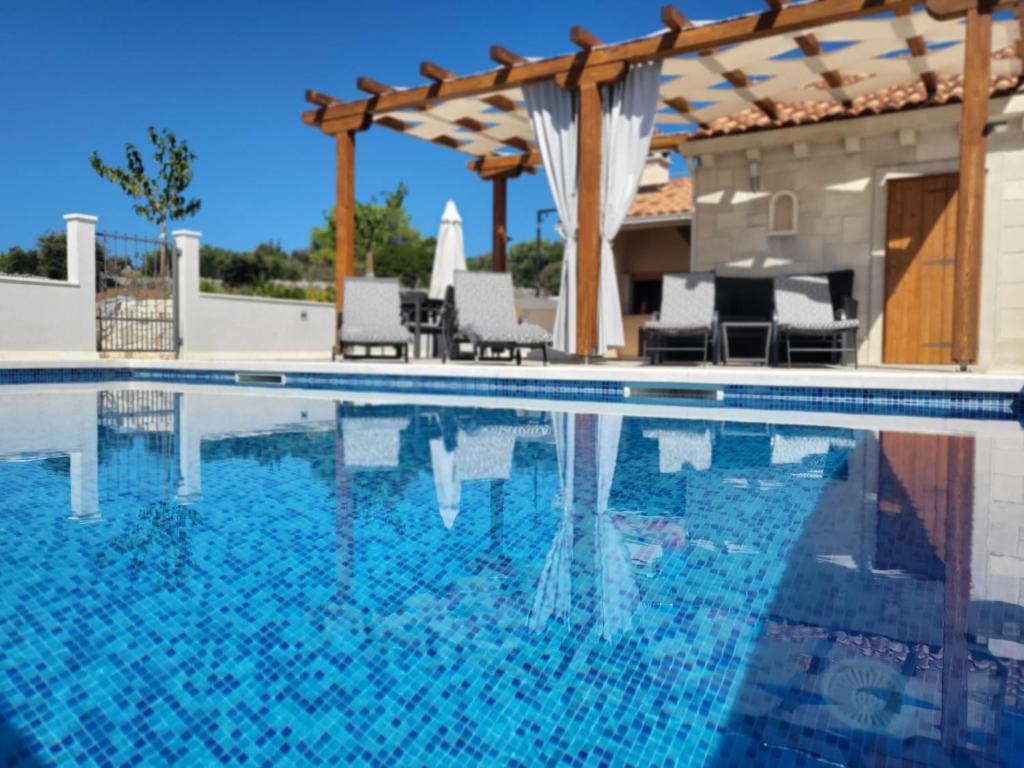 塞尔察Villa Ancora的一个带椅子和凉亭的游泳池