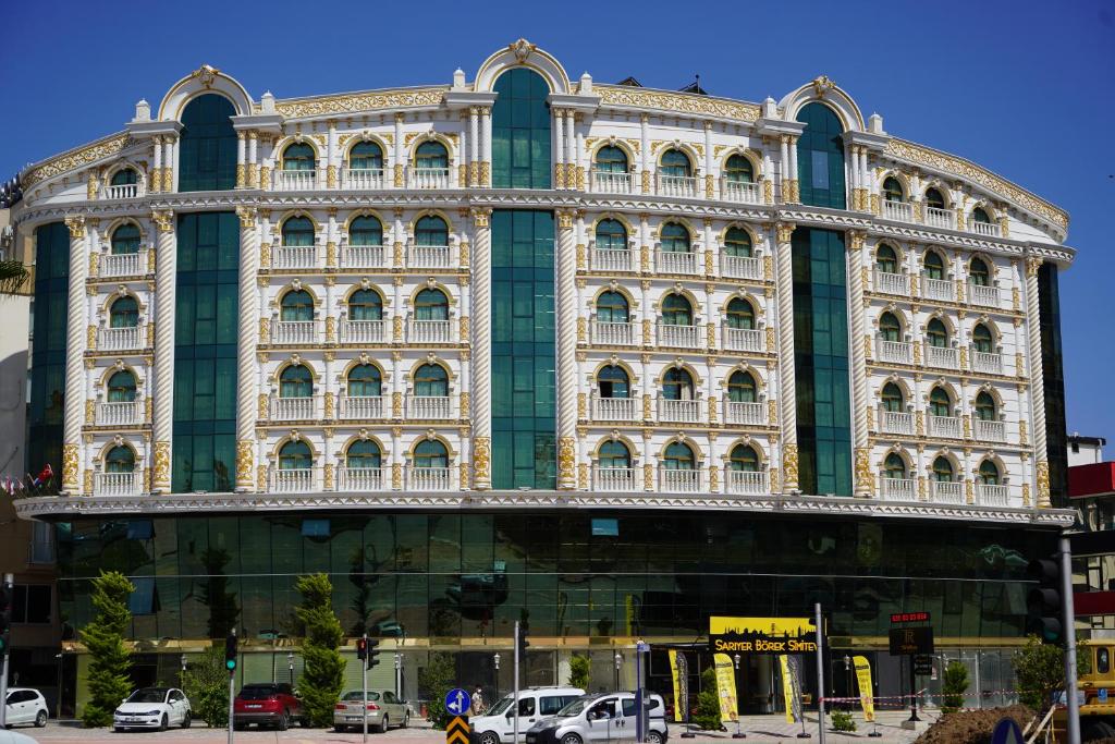 安塔利亚Can Adalya Palace Hotel的一座大型建筑,前面有汽车停放