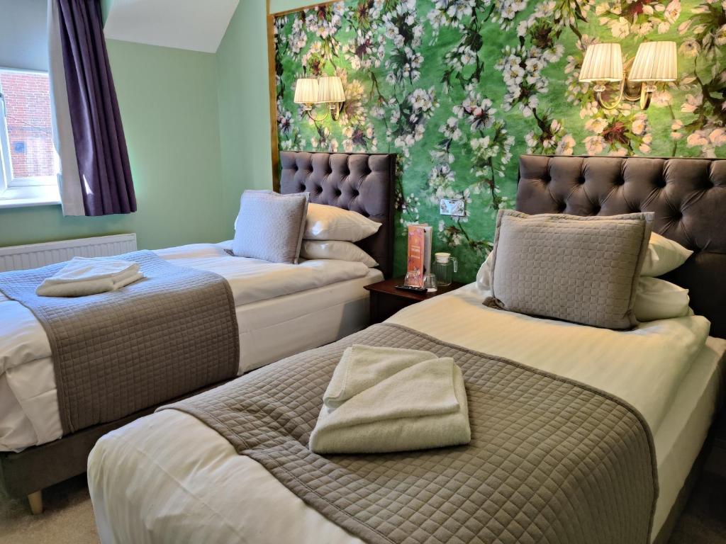 Bingham宾汉姆联排别墅酒店的花卉墙面的客房内的两张床