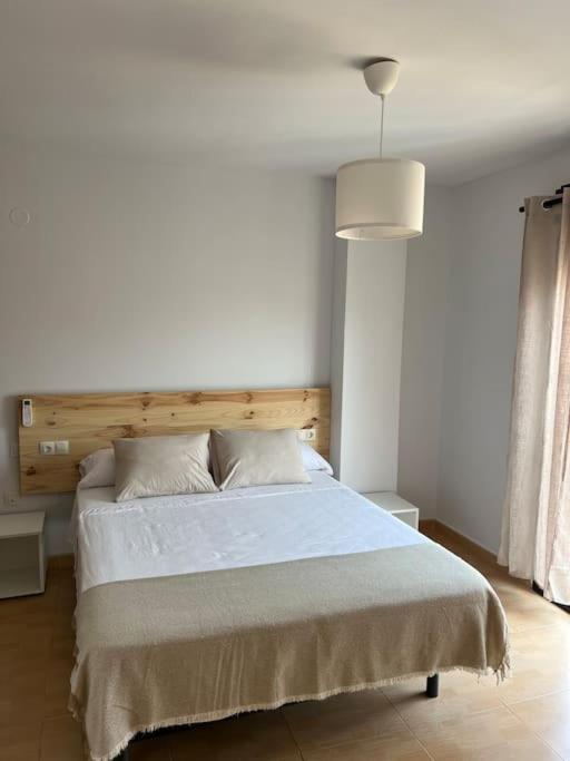 林孔-德拉维多利亚Rincón Costero的卧室配有一张白色大床和木制床头板