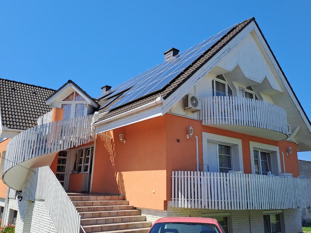 巴拉通雷勒Alinka Apartmanház的一座带太阳能屋顶的橙色房子