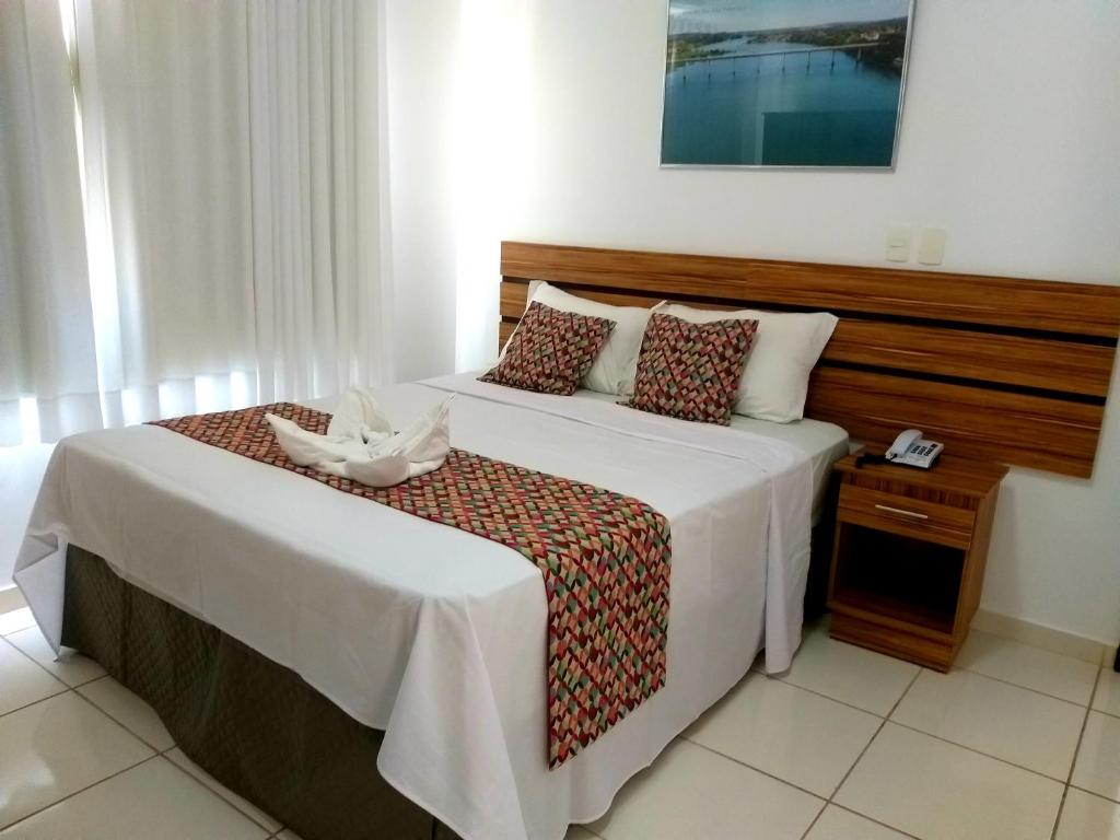 三玛丽亚镇Hotel Estrela Mares的一间卧室配有一张大床和木制床头板