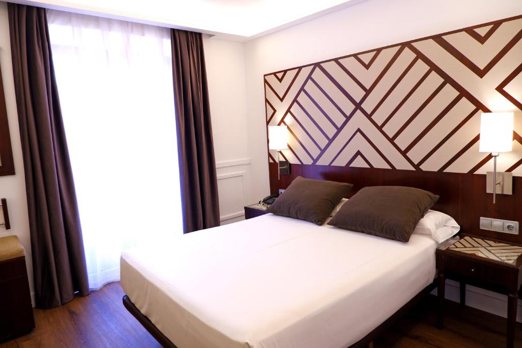 巴利亚多利德阿特里奥精品酒店的一间卧室配有一张大床和木制床头板