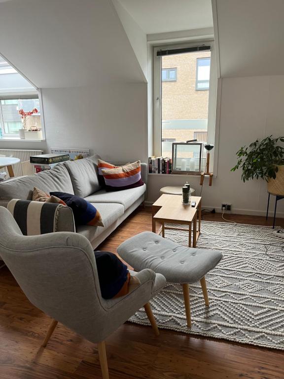 海宁Skøn centralt beliggende lejlighed m.tagterrasse的客厅配有沙发和两把椅子