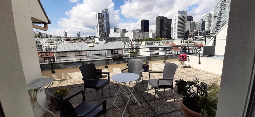 皮托Appartement avec Terrasse à Puteaux 92的阳台配有桌椅,享有城市美景。