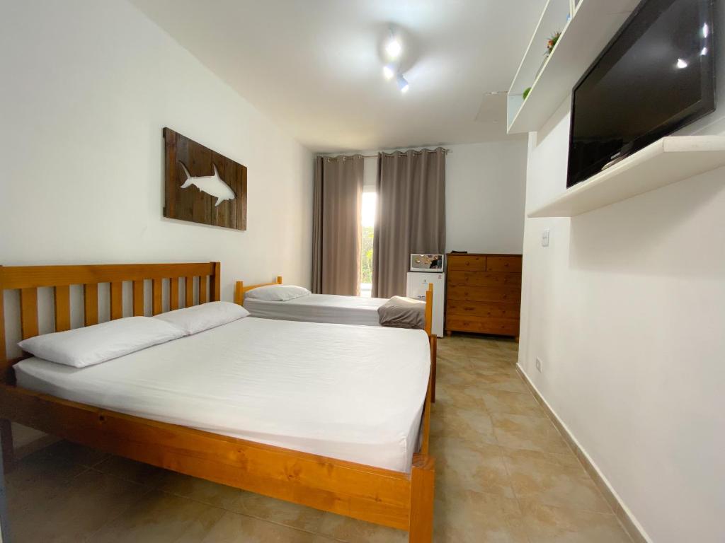 伯迪亚哥SUÍTE PRIVATIVA RIVIERA & ITAGUARÉ 100mts de 2 praias!的一间卧室配有两张床和一台平面电视