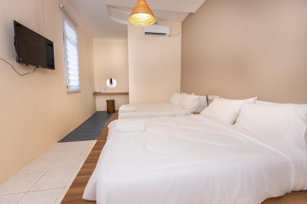 乔治市The Bahari Lodge @ Georgetown的卧室配有一张白色大床和一台平面电视。