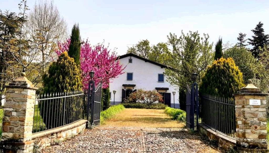 SavignoCasa Stella Country House的白色的房子,有黑色的栅栏和树木