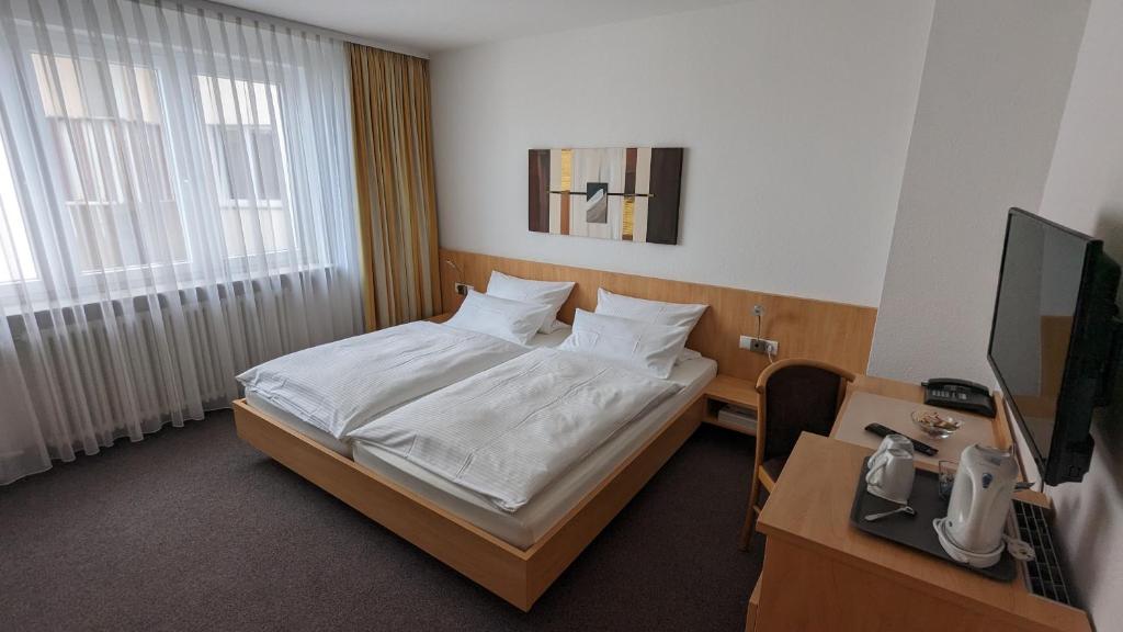 斯图加特齐格勒加特豪斯酒店的一间卧室配有一张床、一张书桌和一台电视