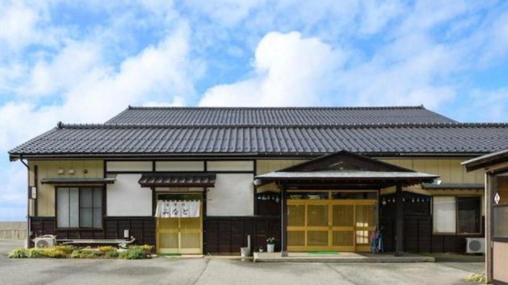 佐渡市Sado Ryosou Minato的一座建筑,有黑色的屋顶和黄色的门