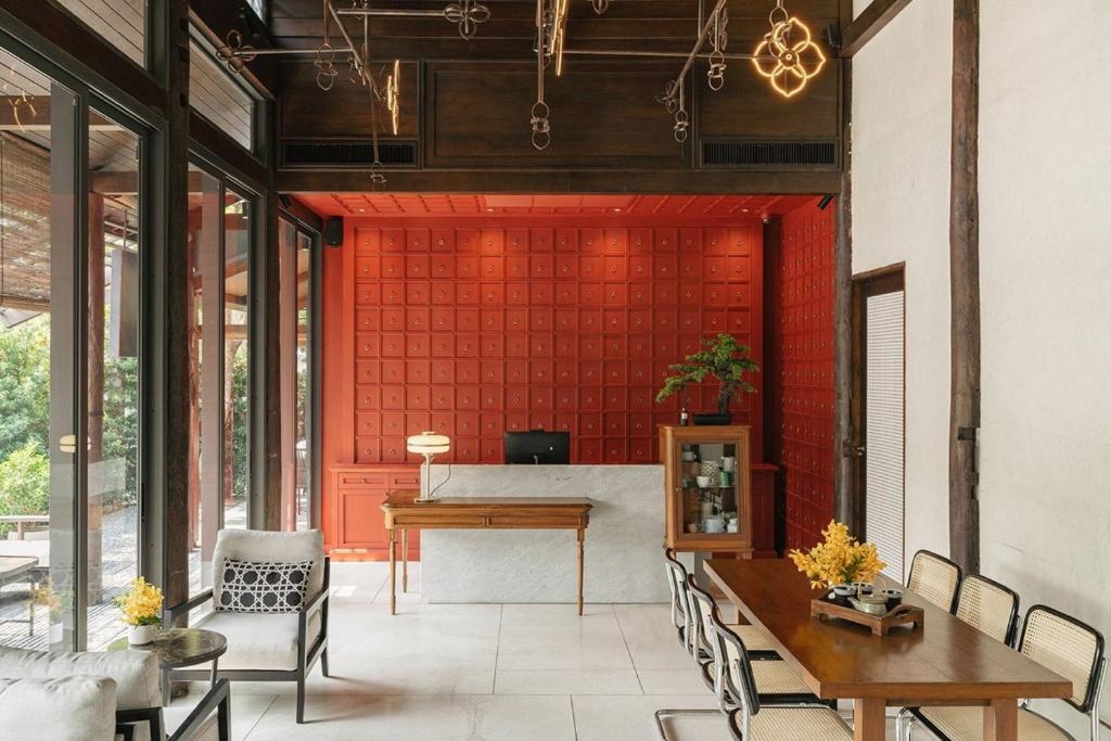 清迈Hotel Loy Chiang Mai的客厅设有红色的墙壁和桌椅