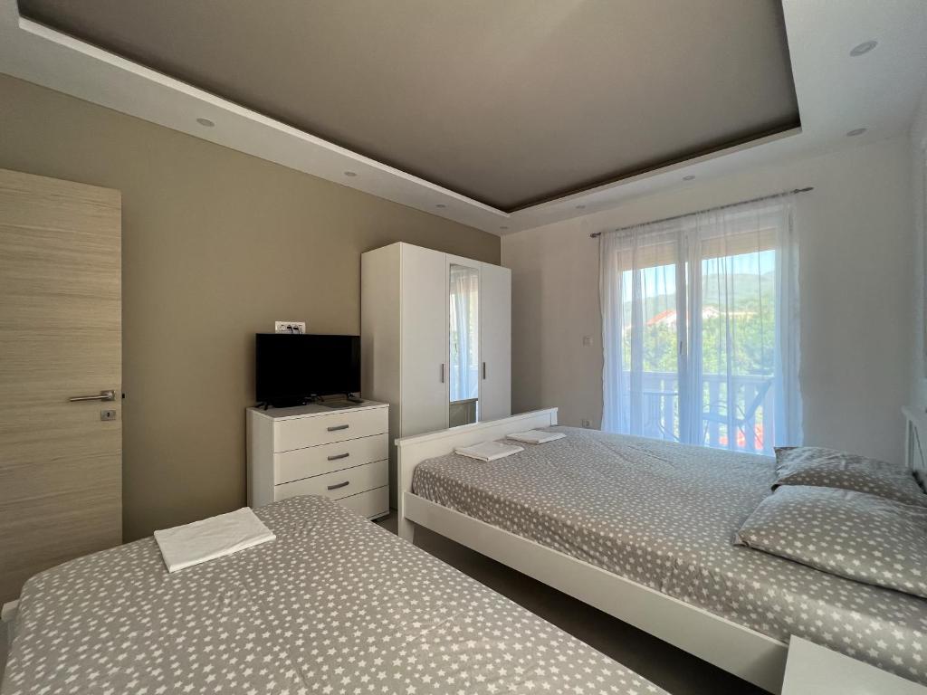 蒂瓦特Mavalux apartments的一间卧室设有两张床、一台电视和一扇窗户。