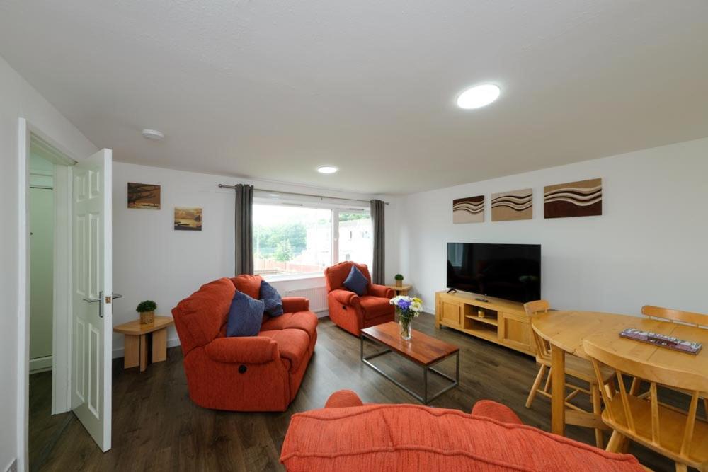 罗塞斯Premier Apt - Bridge View-Rosyth的客厅配有两把橙色椅子和电视