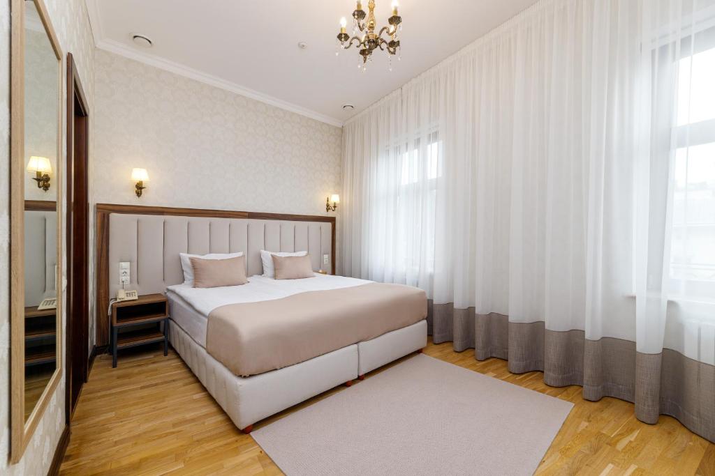 利沃夫Feder Boutique Hotel的卧室配有一张白色大床和吊灯。