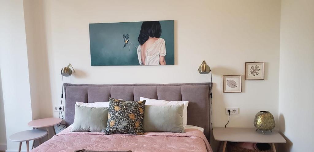 阿拉木图Cozy Urban Retreat的一间卧室配有粉红色的床,上面有绘画作品