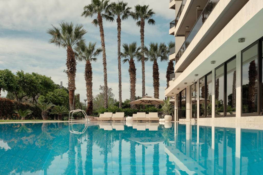 雅典金太阳酒店的酒店游泳池的背景是棕榈树