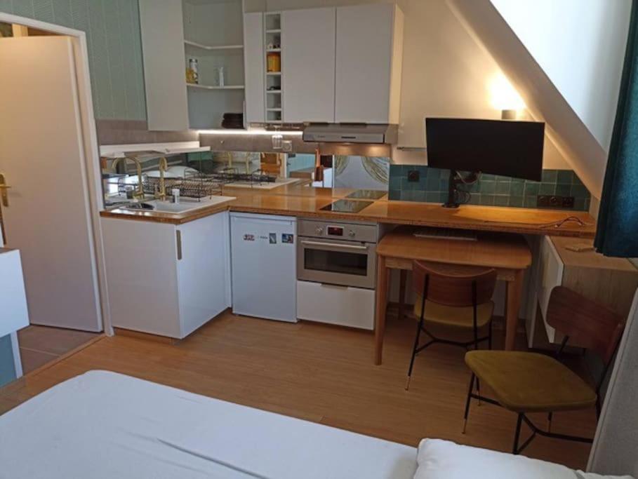 多维尔Appartement, place Morny.的厨房配有白色橱柜和带电脑的书桌