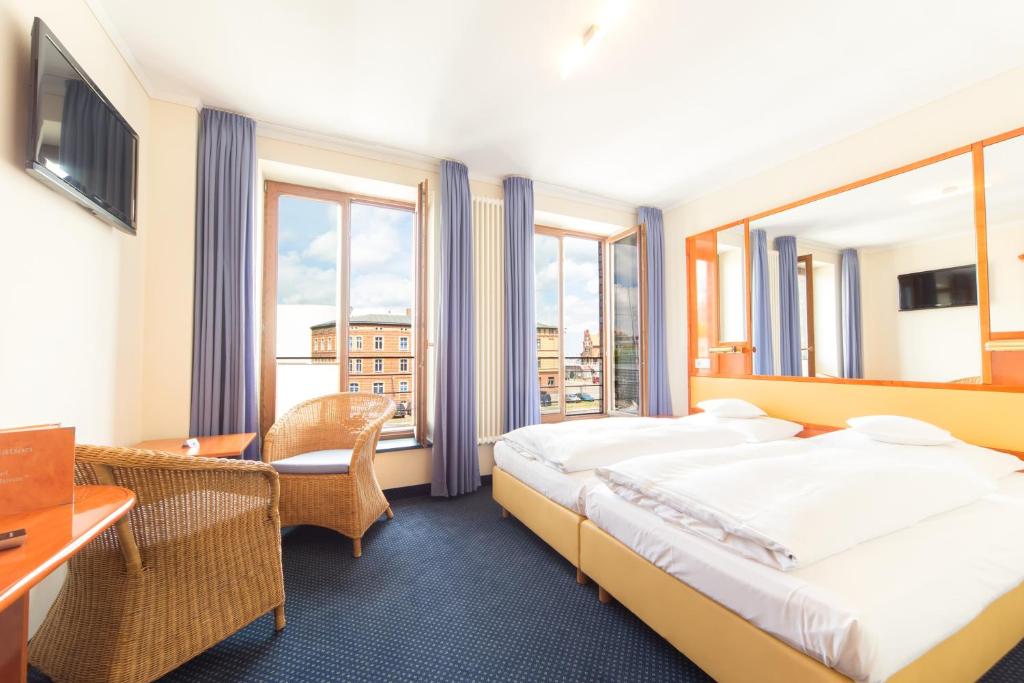 施特拉尔松德Hotel Kontorhaus Stralsund的酒店客房设有一张床、一张书桌和窗户。