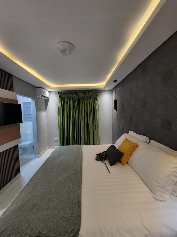 哈博罗内Josmot Guest House的一间卧室配有一张带绿帘的大床