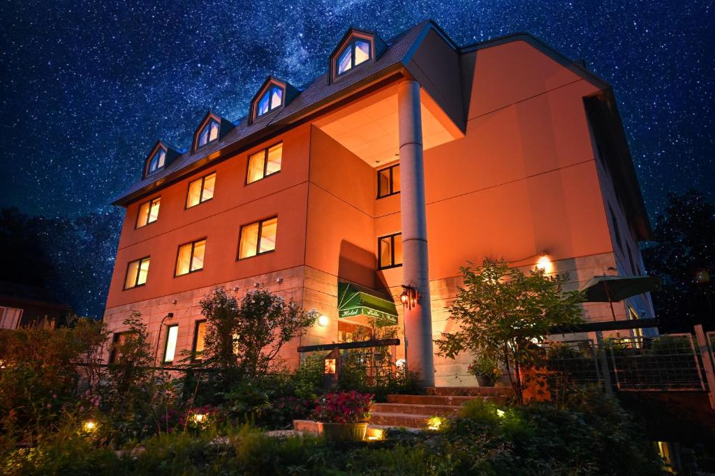 白马村斯黛拉百丽酒店的一座橙色的建筑,夜晚有星空