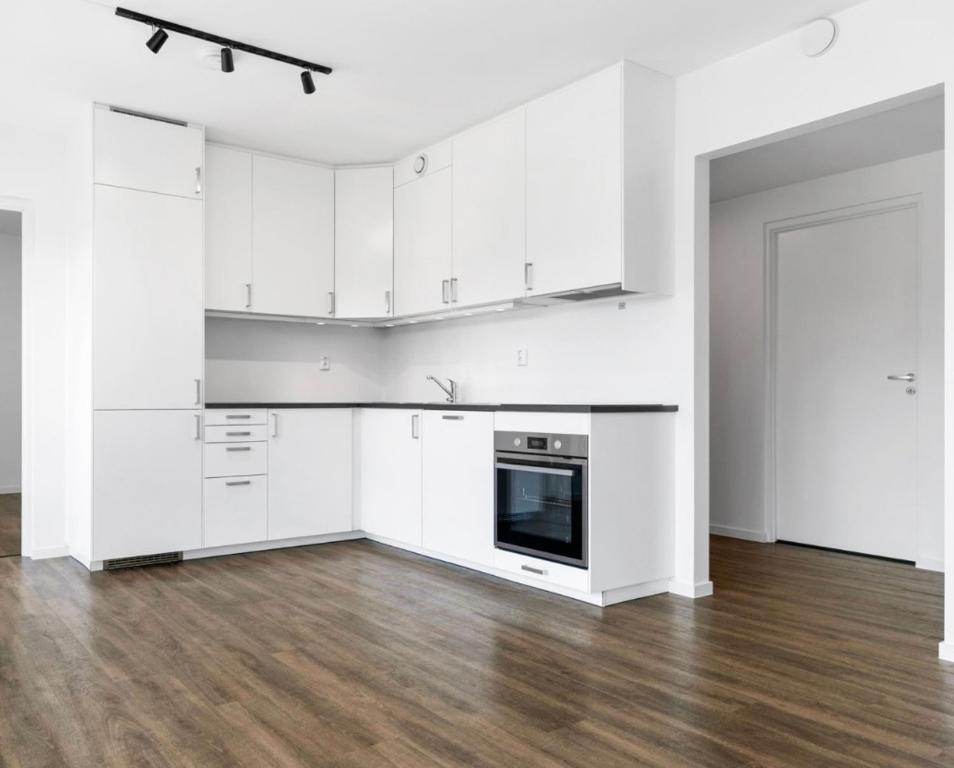 RødFamily-Friendly Apartment的白色的厨房配有白色橱柜和木地板