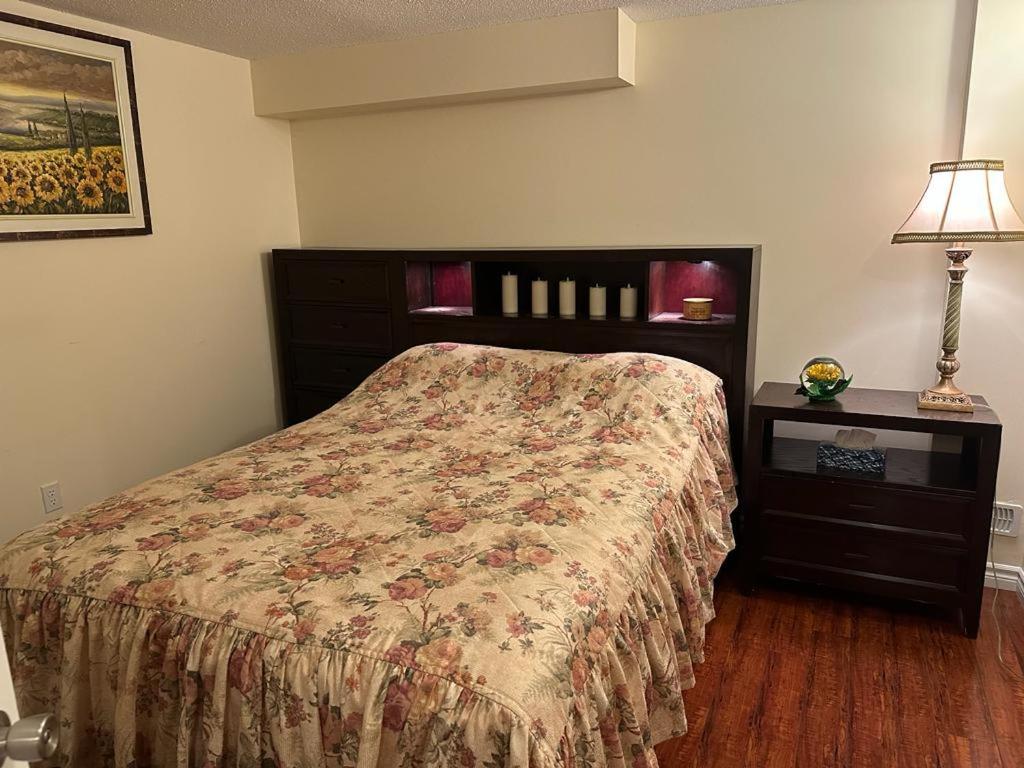 列治文山Basement apartment的一间卧室配有一张床和一张带台灯的桌子