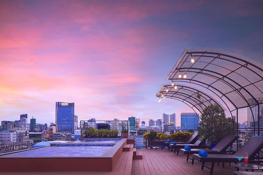 金边欧汉娜金边皇宫酒店的一个带椅子的屋顶游泳池,享有城市美景