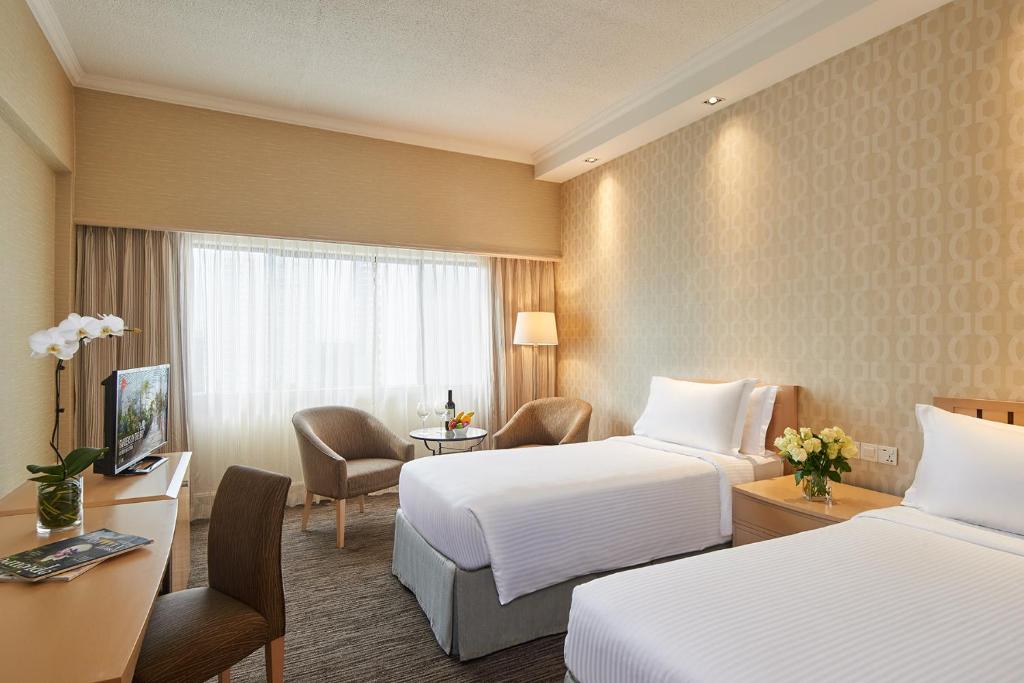 新加坡York Hotel的酒店客房,配有两张床、椅子和桌子