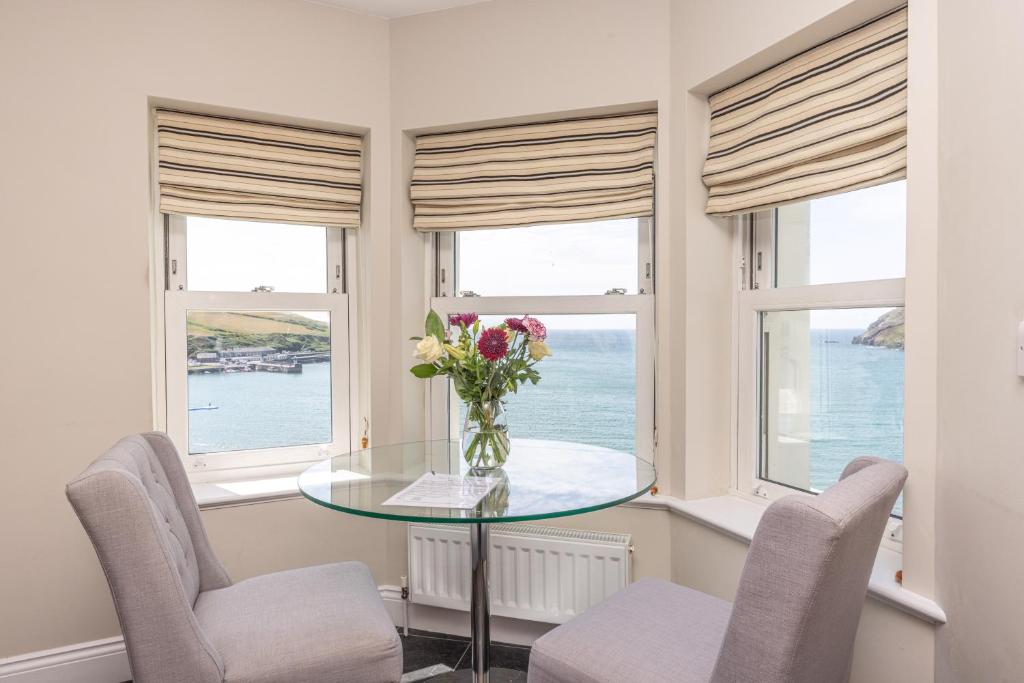 伊林港湾景公寓的一间设有窗户和花卉玻璃桌的用餐室