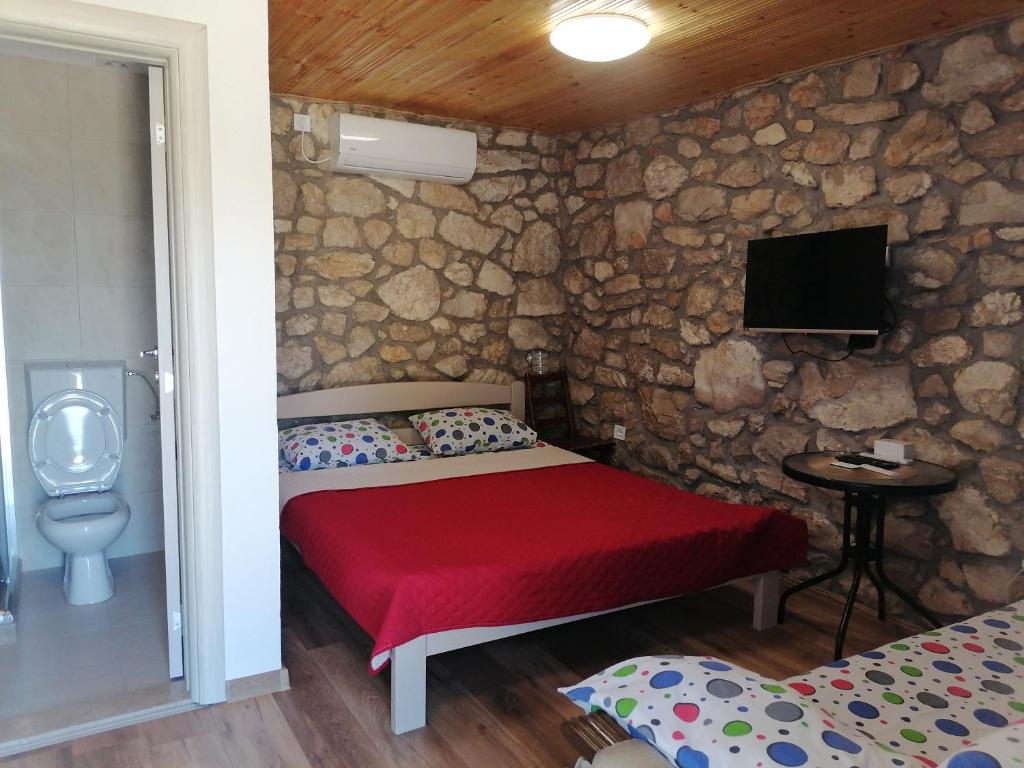 DanilovgradApartmani Perosevic的一间卧室设有一张床,并在石墙内配有电视。