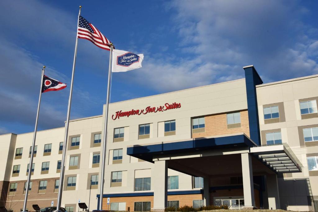 西切斯特Hampton Inn & Suites Cincinnati Liberty Township的两面旗帜在建筑物前飞