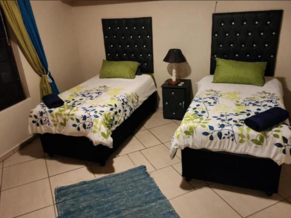 MtubatubaThe Sanctuary - Self Catering Accommodation的一间卧室配有两张床、一盏灯和一张地毯。