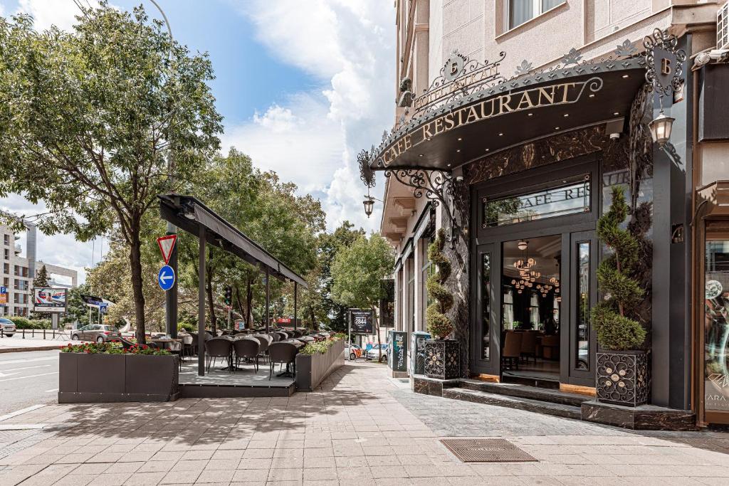 贝尔格莱德Hotel Balkan的大楼前的街道上,有带椅子的餐厅