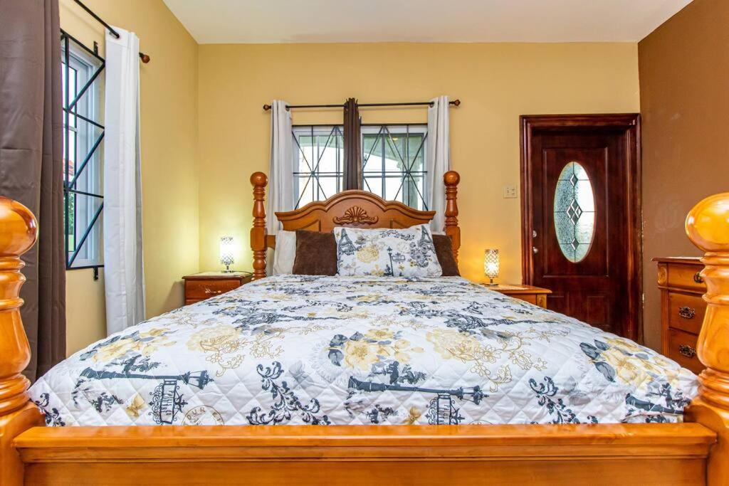Spanish TownJ&R Sunshine Retreat的一间卧室配有一张带蓝色和白色棉被的床