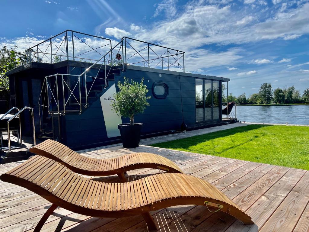 芬克芬NEW - Little Asia - Stunning Boathouse on al lake Near Amsterdam的木凳坐在房子旁边的甲板上