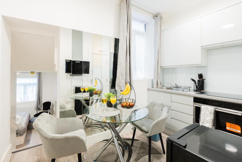 伦敦Large Studio Apartment 30 mins to Oxford Street (B)的白色的厨房配有玻璃桌和椅子