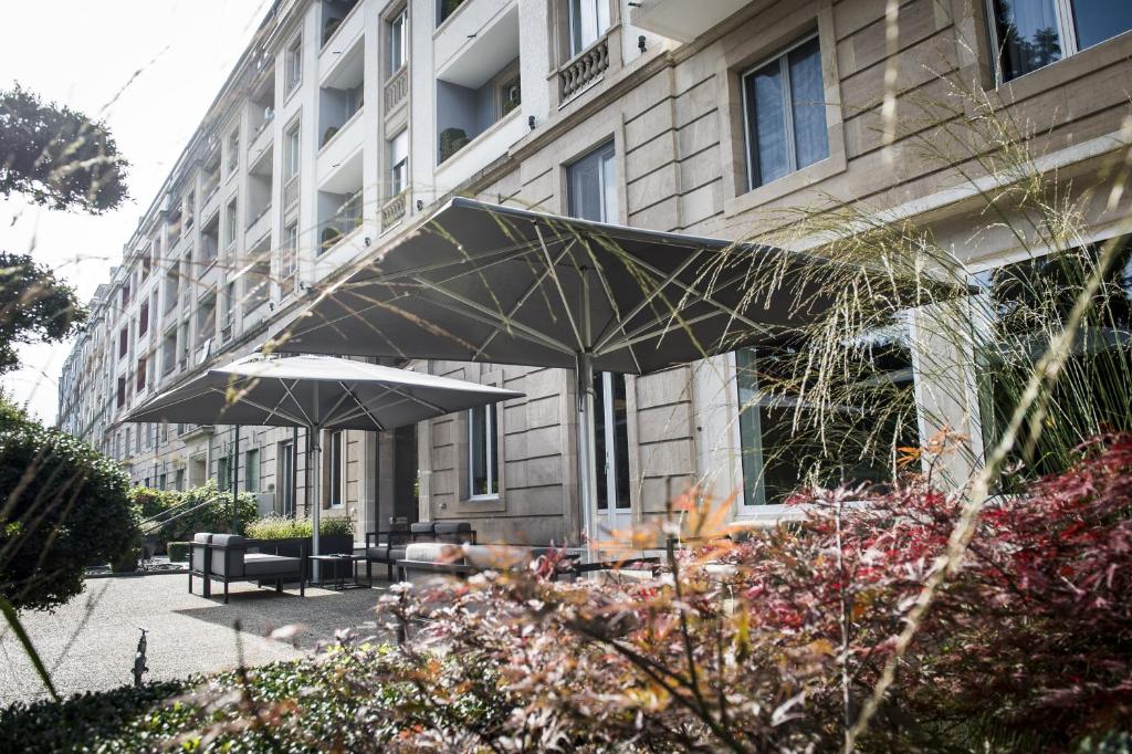 日内瓦蒙里普斯酒店的前面有两张桌子和遮阳伞的建筑