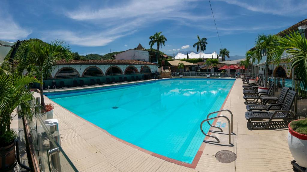 布卡拉曼加Hotel San Juan Internacional的一个带椅子和棕榈树的大型蓝色游泳池