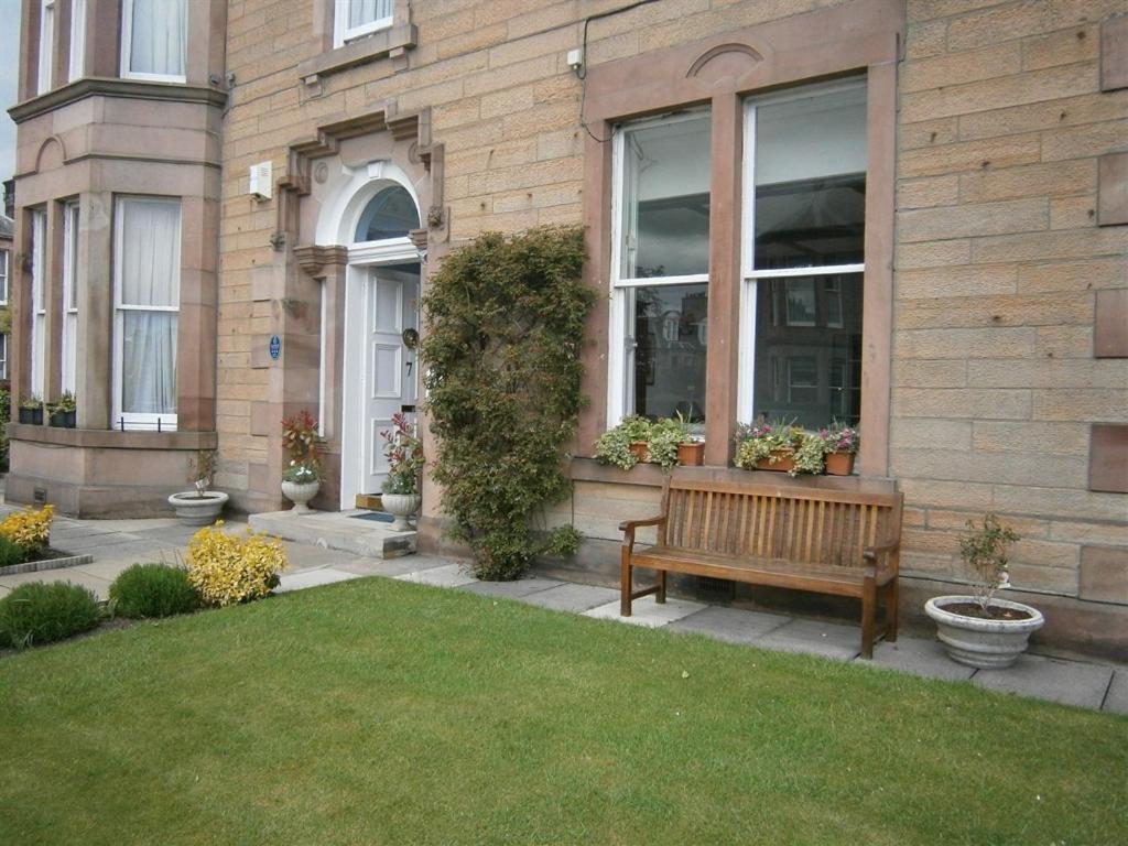 爱丁堡Dorstan House的坐在大楼前的草上木凳
